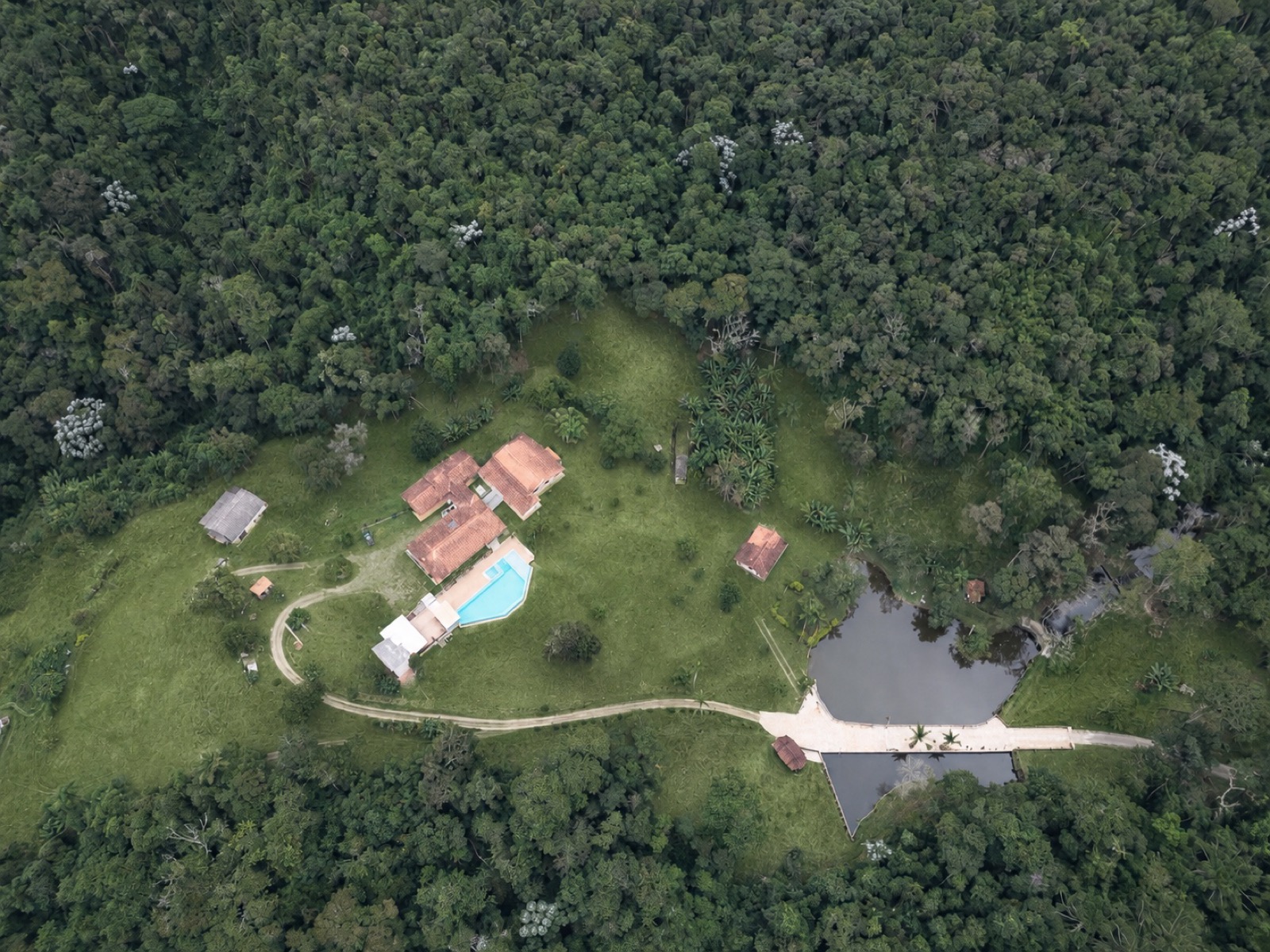 Vista aérea atual do Sítio Serra Serena com piscina, lago e mata