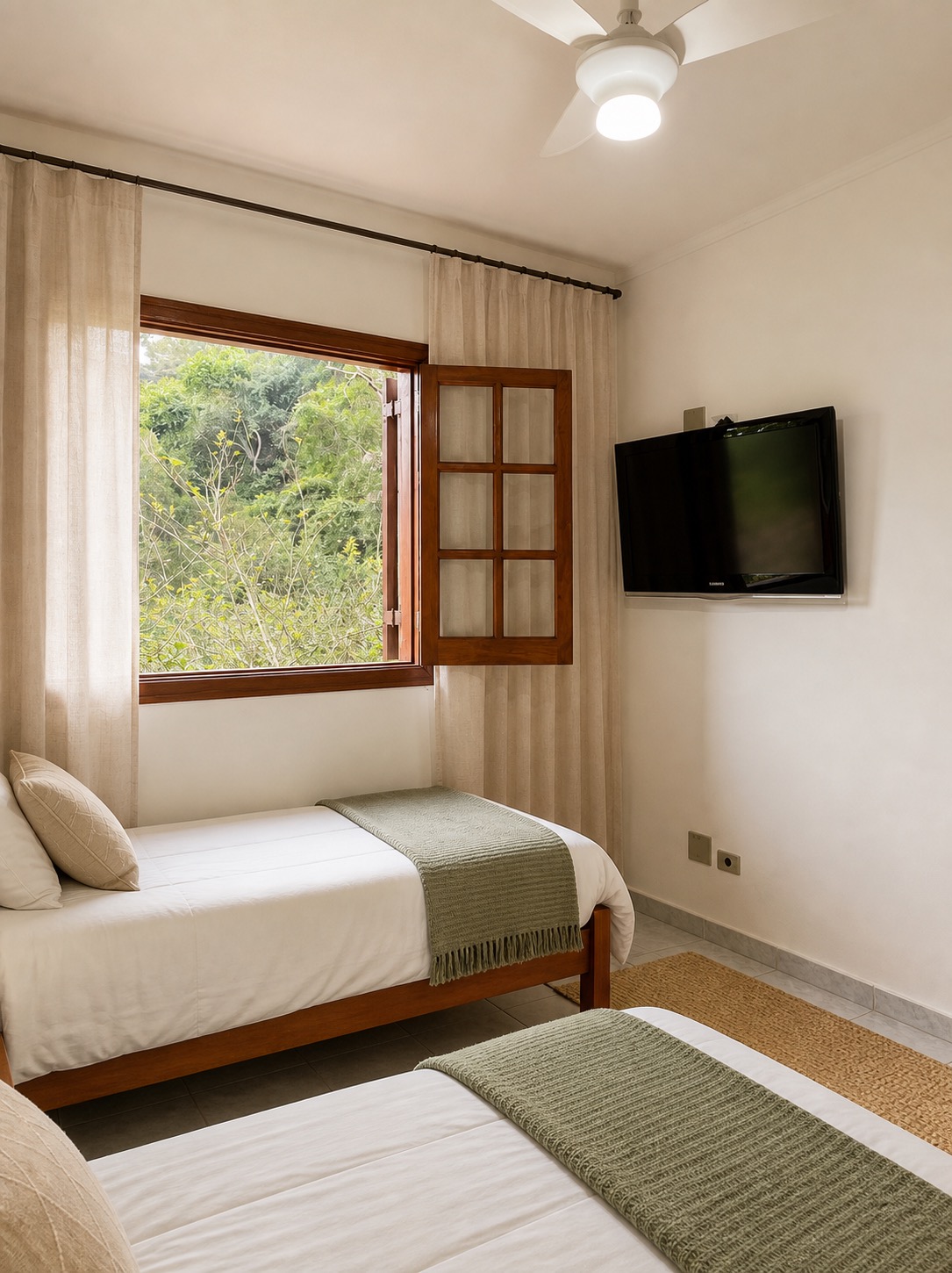 Vista do quarto da Suíte 3 com camas de solteiro arrumadas e janela de madeira aberta para a mata