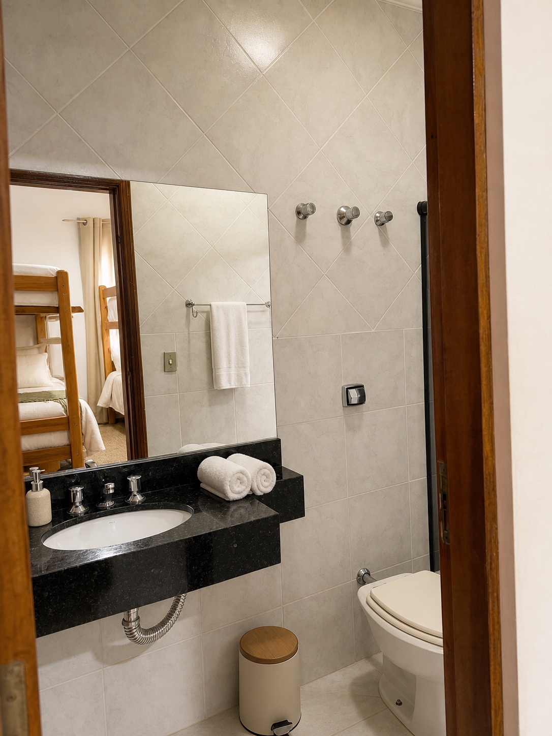 Banheiro privativo da Suíte 4 visto pela porta de madeira, com vanity em granito e box de vidro